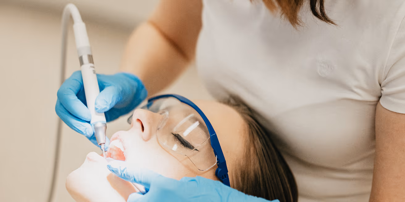 Dentální hygienistka Premier Clinic při profesionálním čištění zubů
